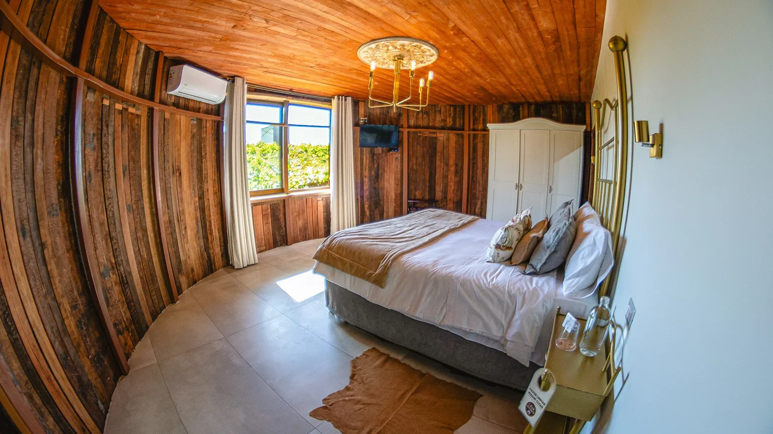 Habitación con muros curvos de madera en Hotel Santa Cruz, cama amplia y luz natural.