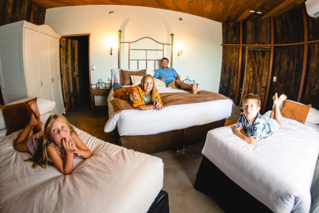 Familia descansando en habitación rústica de Hotel Santa Cruz, con tres camas y detalles en madera.